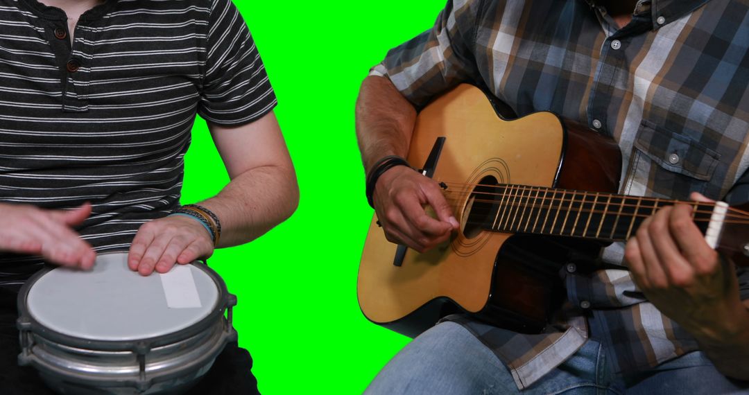 Mid section of male musicians playing guitar and drum against green screen - Free Images, Stock Photos and Pictures on Pikwizard.com