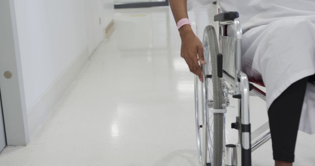 Hospital Patient Using Wheelchair in Medical Facility Hallway - Free Images, Stock Photos and Pictures on Pikwizard.com