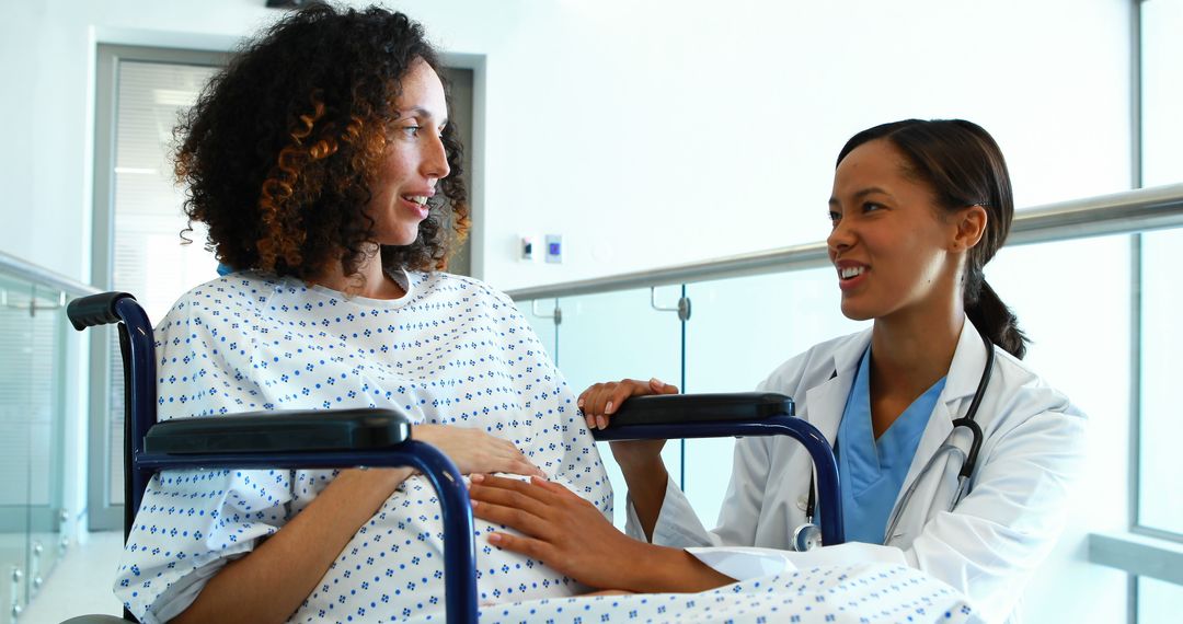 Pregnant woman in wheelchair receiving care from smiling female doctor - Free Images, Stock Photos and Pictures on Pikwizard.com