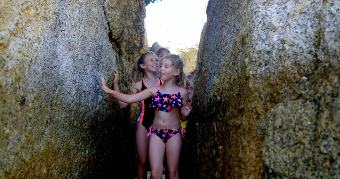 Smiling Kids Exploring Rocky Crevice in Swimsuits - Free Images, Stock Photos and Pictures on Pikwizard.com