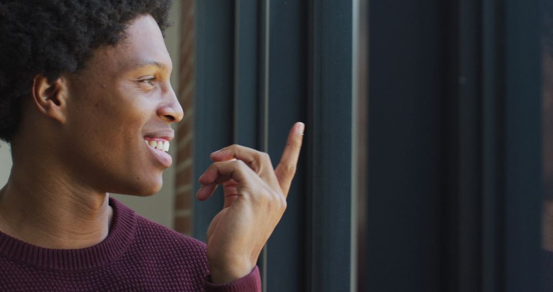 Content African American Man Looking Out Window Smiling