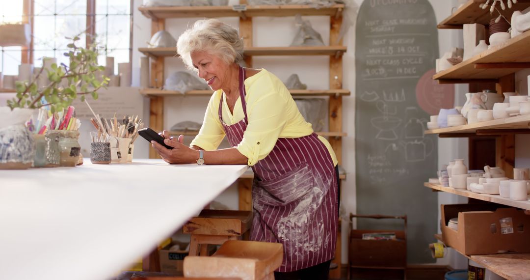 Senior Woman in Pottery Studio Using Smartphone - Free Images, Stock Photos and Pictures on Pikwizard.com