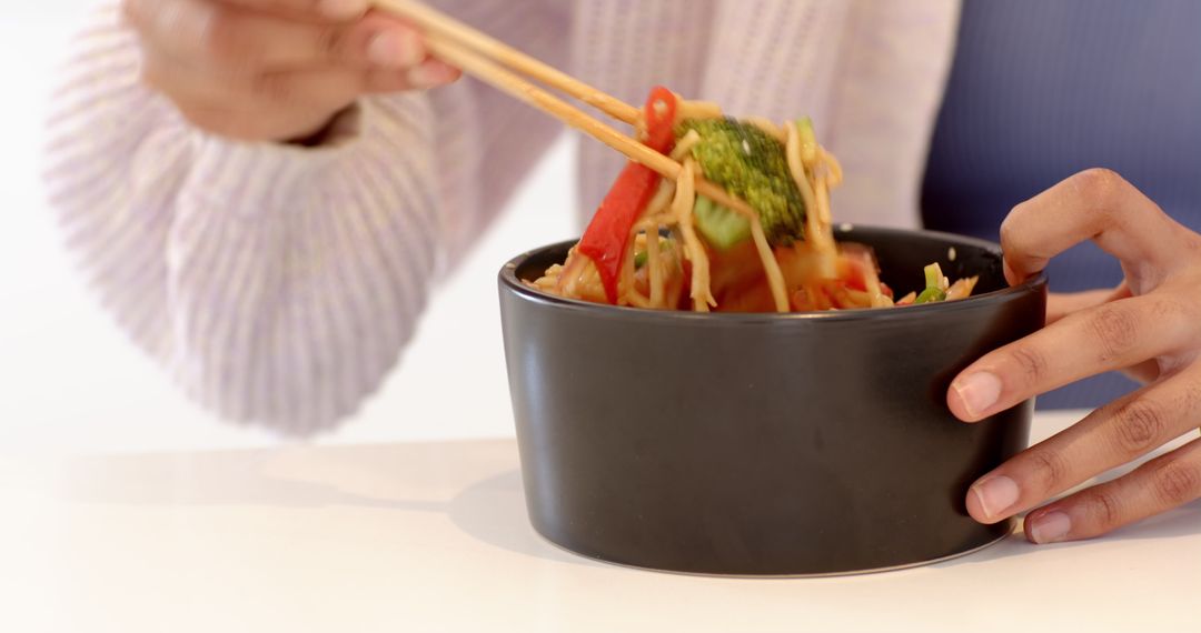 Woman Enjoying Stir-Fried Noodles with Chopsticks Close-up at Home