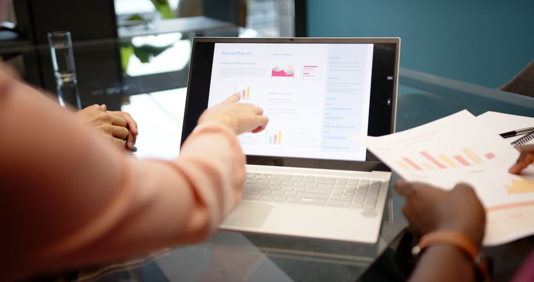 Team Analyzing Annual Report on Laptop in Modern Office