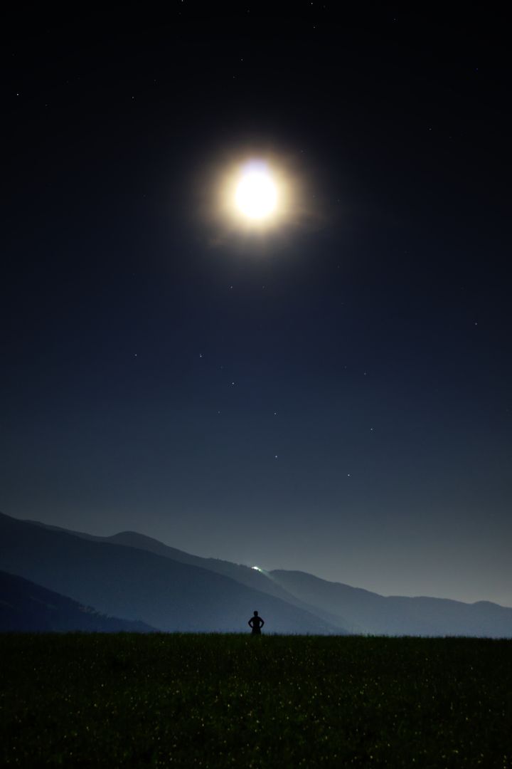 Silhouette of Person Admiring Bright Moonlit Night Sky in Mountains - Free Images, Stock Photos and Pictures on Pikwizard.com