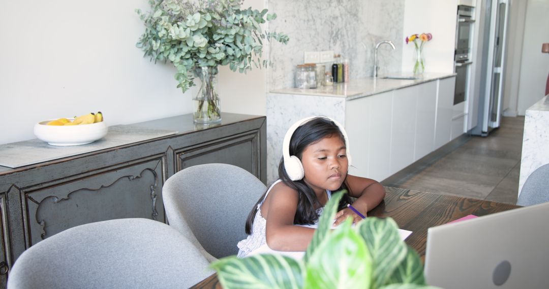 Child Engaged in Learning with Laptop and Headphones in Kitchen