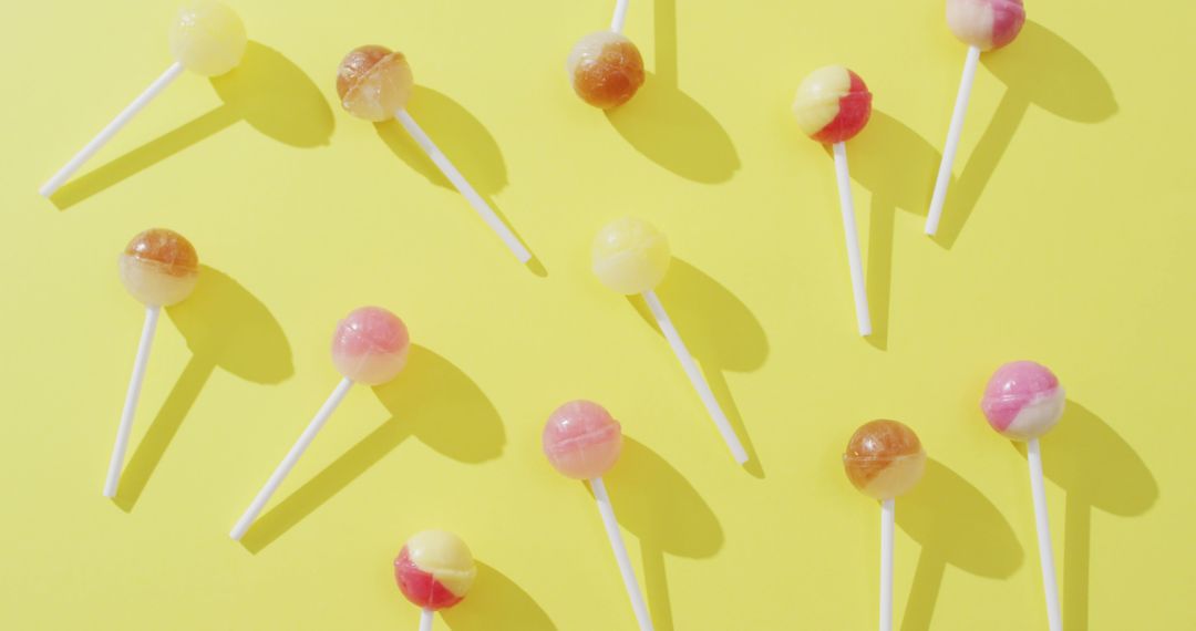Image of multicoloured lollipops on yellow background - Free Images, Stock Photos and Pictures on Pikwizard.com