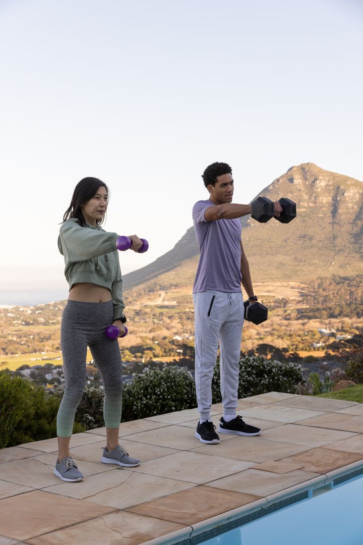 Diverse Friends Exercising with Dumbbells by Scenic Open Poolside