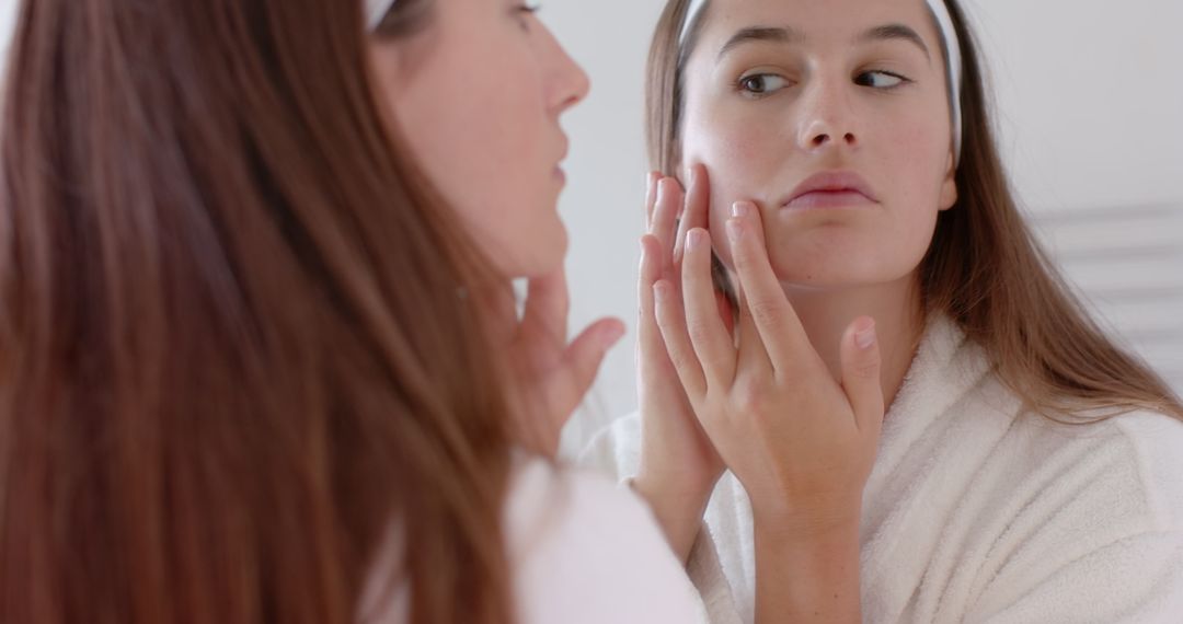Young Woman Examining Skin in Mirror for Skincare Routine