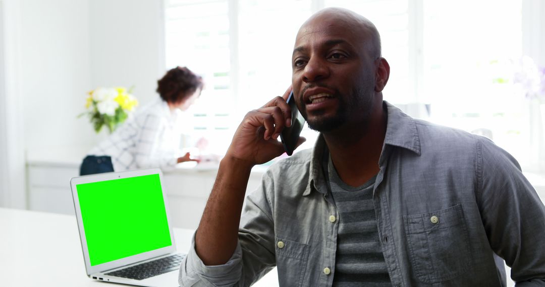 Man Talking on Phone Near Laptop with Green Screen in Bright Office - Free Images, Stock Photos and Pictures on Pikwizard.com