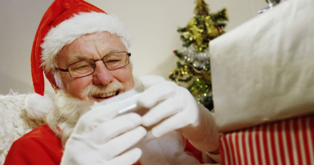 Santa Claus Opening Christmas Present with Joyful Expression - Free Images, Stock Photos and Pictures on Pikwizard.com