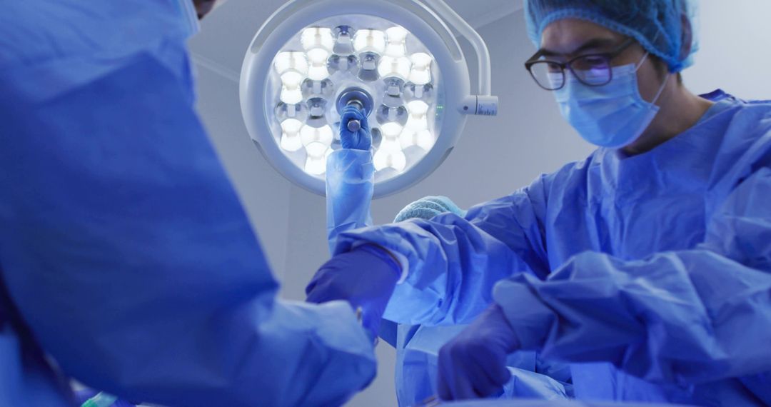 Surgical team preparing instruments under LED operating light in hospital operating room