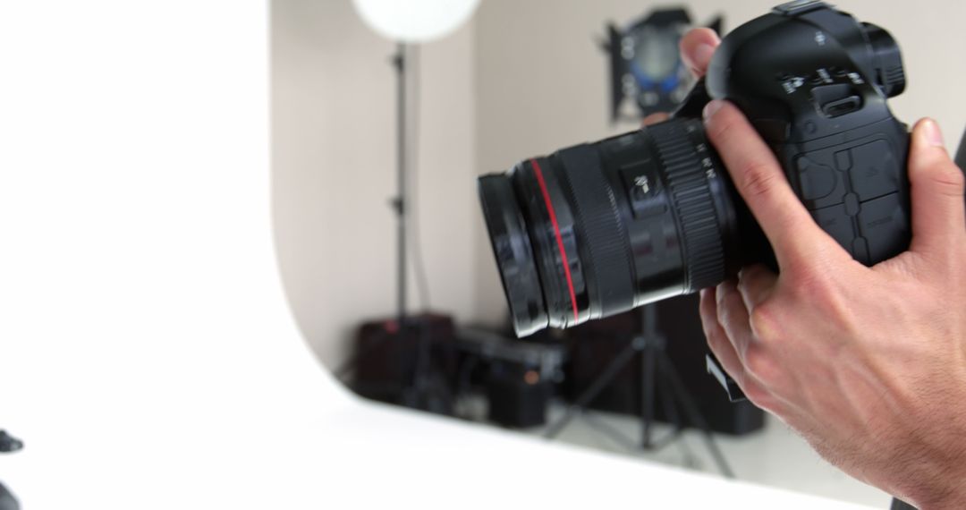 Photographer Holding DSLR Camera in Studio Setting - Free Images, Stock Photos and Pictures on Pikwizard.com