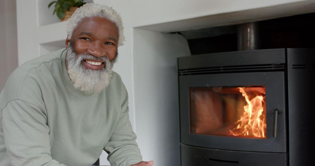 Senior Man Enjoying Warmth of Fireplace at Home