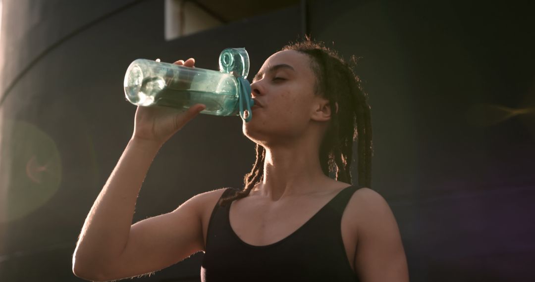 Young Woman Hydrating After Urban Workout at Sunset