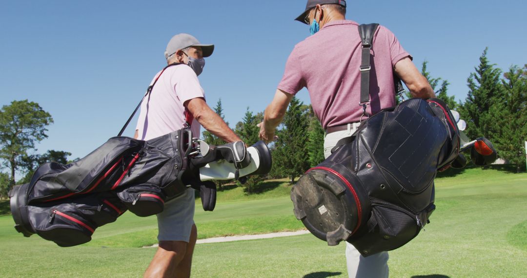 Two Young Male Golfers Wearing Protective Masks Carrying Golf Bags on Green Course - Free Images, Stock Photos and Pictures on Pikwizard.com