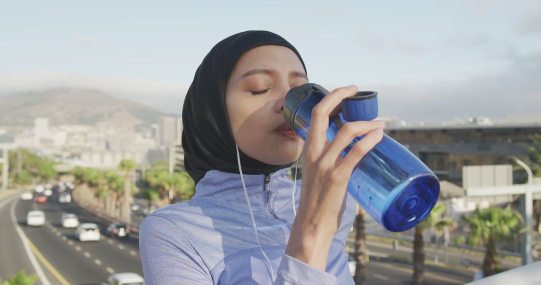 Young Muslim Woman in Hijab Drinking Water During Outdoor Workout - Free Images, Stock Photos and Pictures on Pikwizard.com