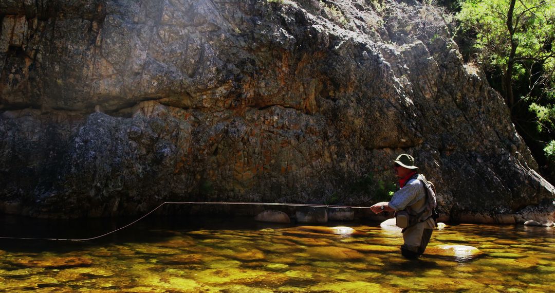 Fisherman Fly Fishing in Shallow River against Rocky Cliff - Free Images, Stock Photos and Pictures on Pikwizard.com