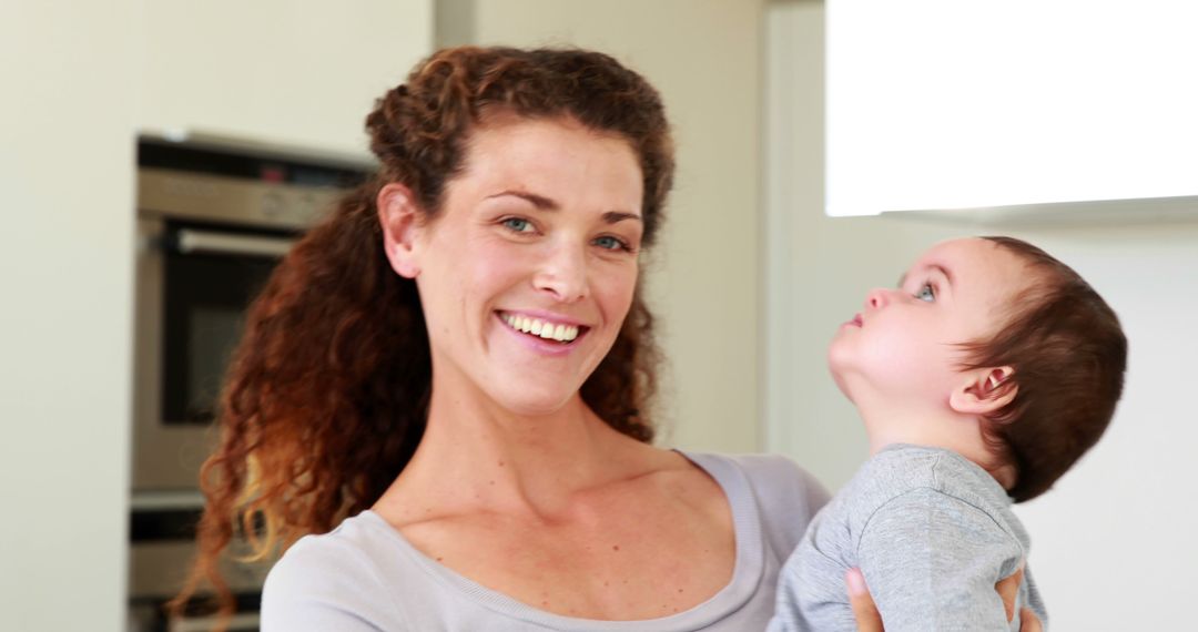 Mother Smiling Holding Baby in Kitchen