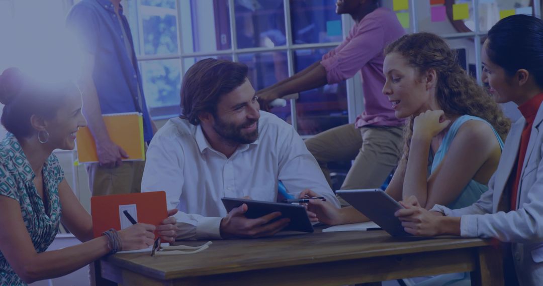 Creative Team Collaborating Around Tablet in Modern Office with Sticky Notes, Glass Wall