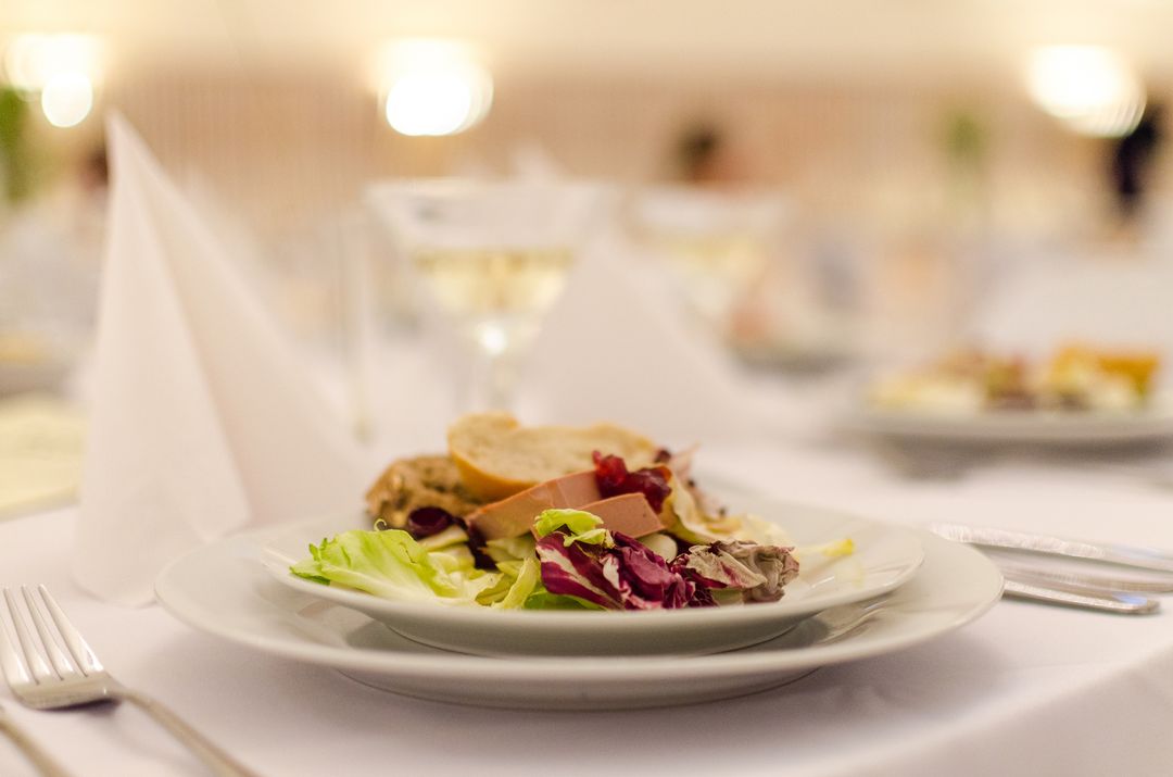 Elegant plated appetizer with mixed salad and foie gras on white linen for formal banquet
