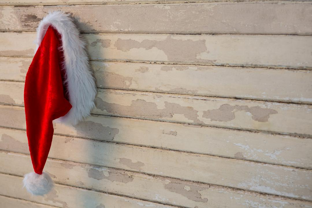 Santa Hat Hanging on Rustic Wooden Wall During Christmas - Free Images, Stock Photos and Pictures on Pikwizard.com