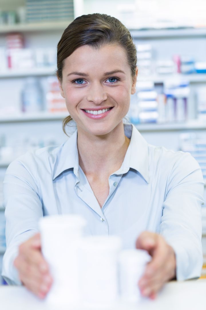 Smiling pharmacist holding medicine container in pharmacy - Free Images, Stock Photos and Pictures on Pikwizard.com