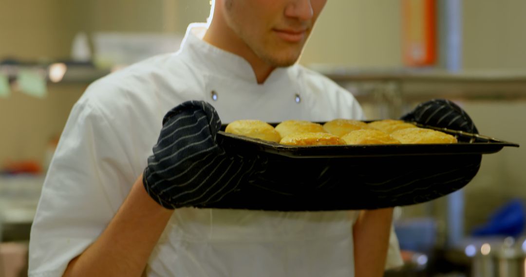 Chef Holding Freshly Baked Bread Rolls in Kitchen - Free Images, Stock Photos and Pictures on Pikwizard.com