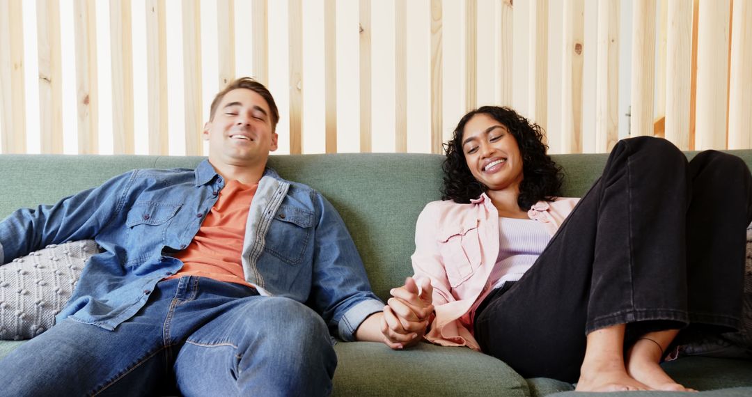 Diverse Couple Relaxing on Sofa, Holding Hands, Enjoying Moment