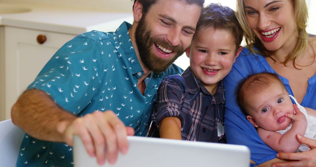 Happy Young Family with Two Kids Smiling While Video Calling on Laptop - Free Images, Stock Photos and Pictures on Pikwizard.com