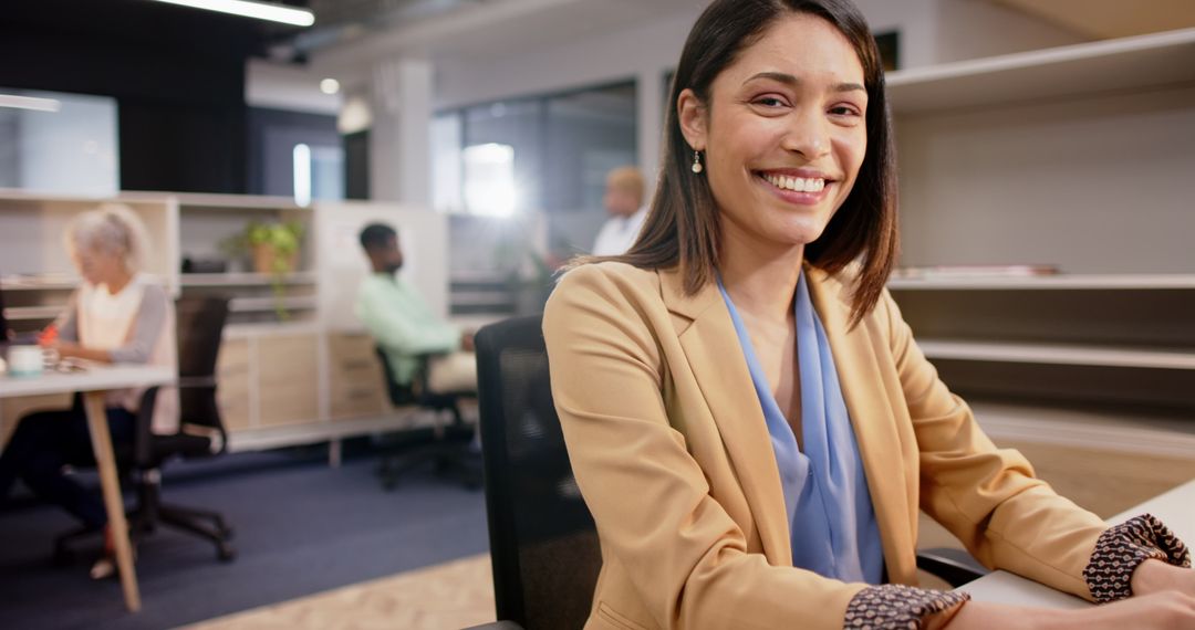 Smiling Businesswoman in Modern Office with Colleagues Collaborating in Background