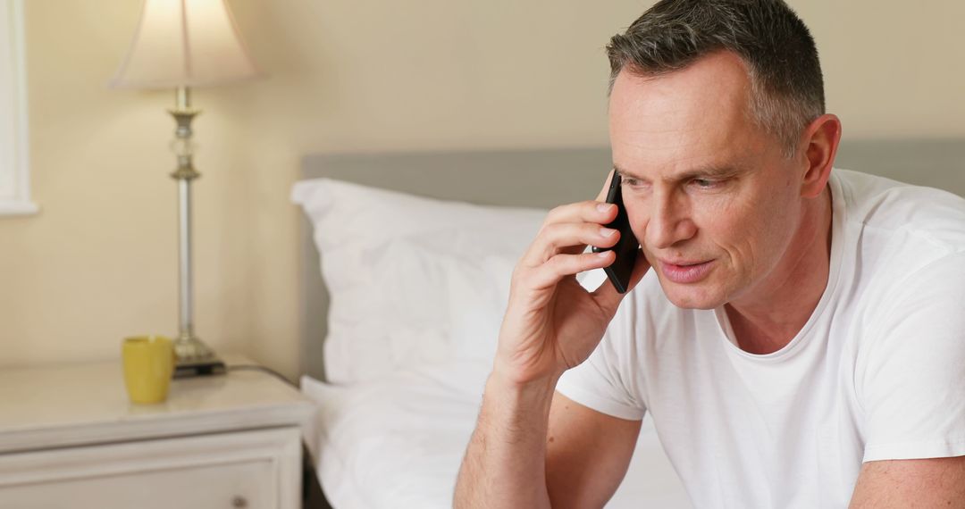 Middle-aged Man Talking on Smartphone in Bedroom - Free Images, Stock Photos and Pictures on Pikwizard.com