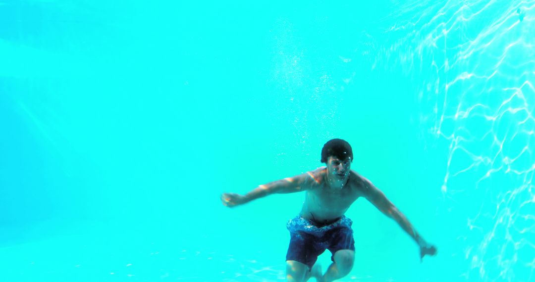 Man Swimming Underwater in Blue Pool with Sunlight Reflections - Free Images, Stock Photos and Pictures on Pikwizard.com