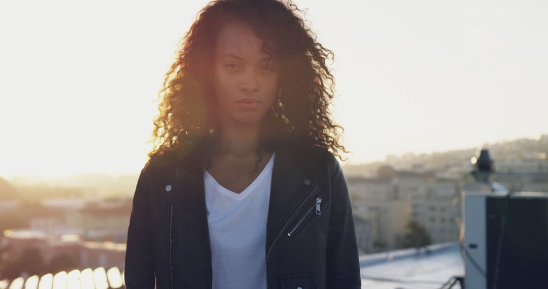 Confident Woman with Curly Hair Standing on Rooftop at Sunset - Free Images, Stock Photos and Pictures on Pikwizard.com