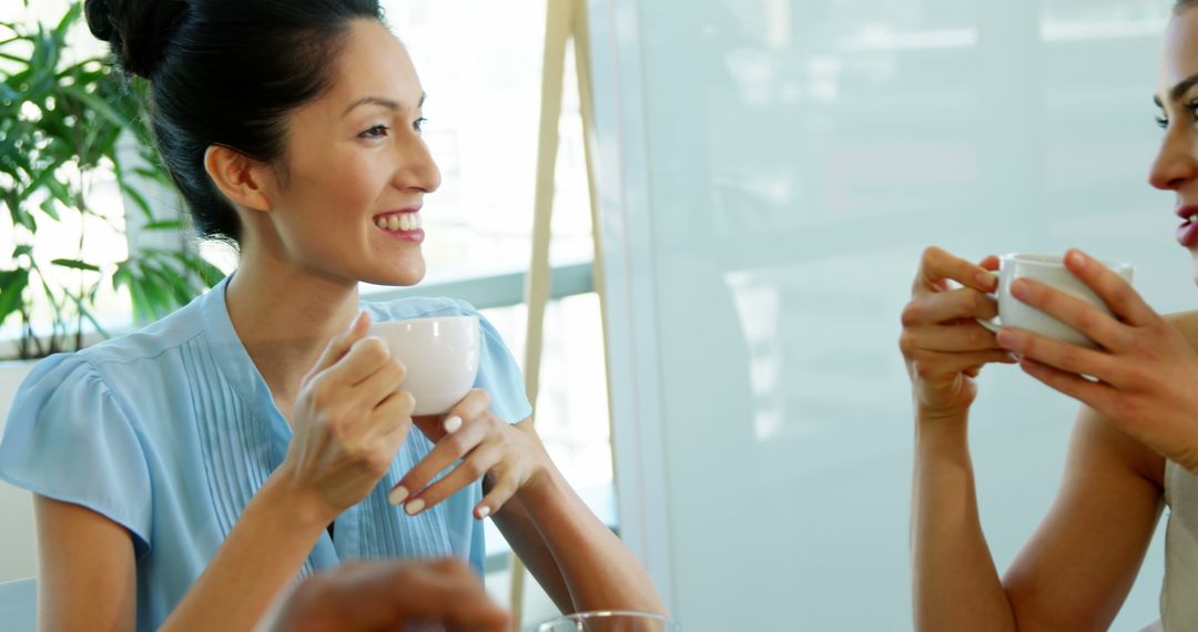 Smiling Businesswomen Discussing Over Coffee in Office - Free Images, Stock Photos and Pictures on Pikwizard.com