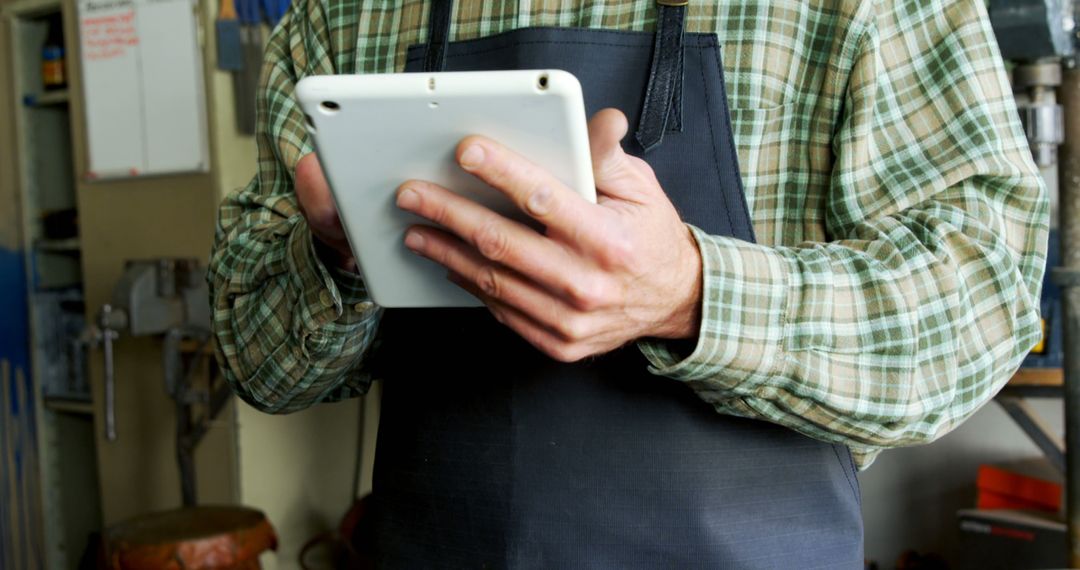 Worker in Apron Using Tablet for Inventory Management in Workshop - Free Images, Stock Photos and Pictures on Pikwizard.com