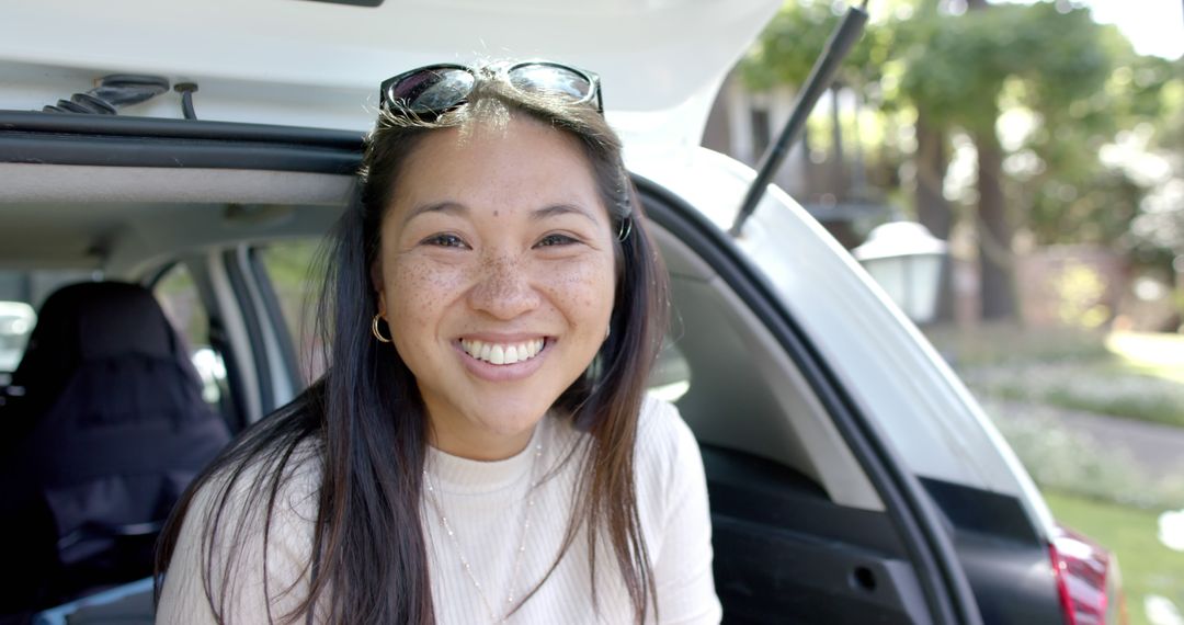 Smiling Young Woman with Sunglasses Sitting in Car Trunk Outdoors - Free Images, Stock Photos and Pictures on Pikwizard.com