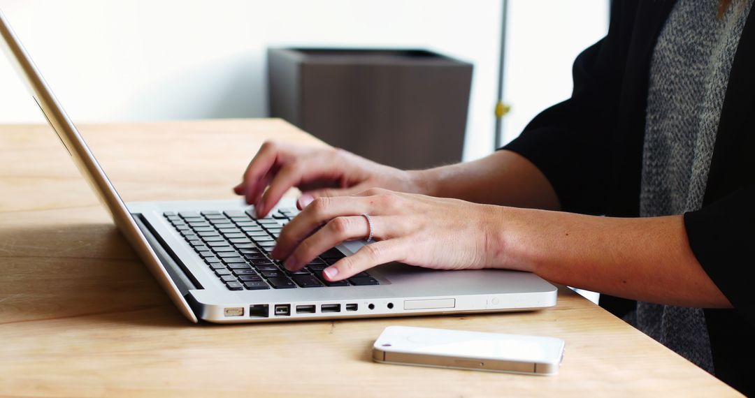 Professional Woman Typing on Laptop at Wooden Desk in Office