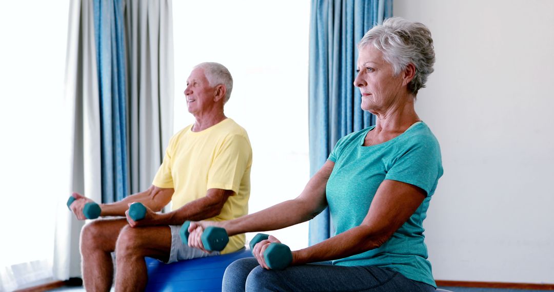 Senior couple exercising with dumbbells in a fitness class - Free Images, Stock Photos and Pictures on Pikwizard.com