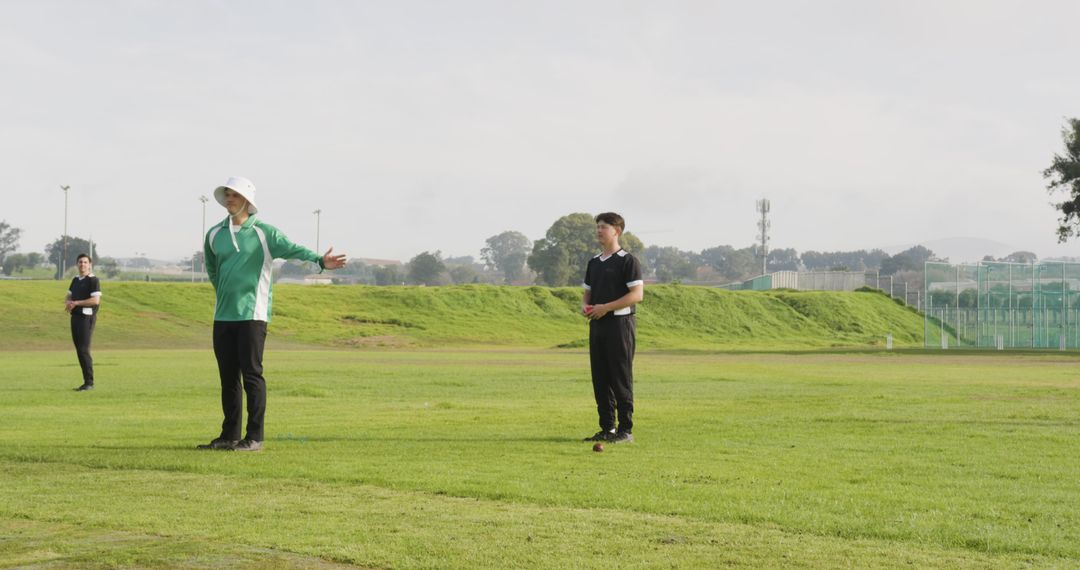 Cricket Coach Instructing Players on Green Field