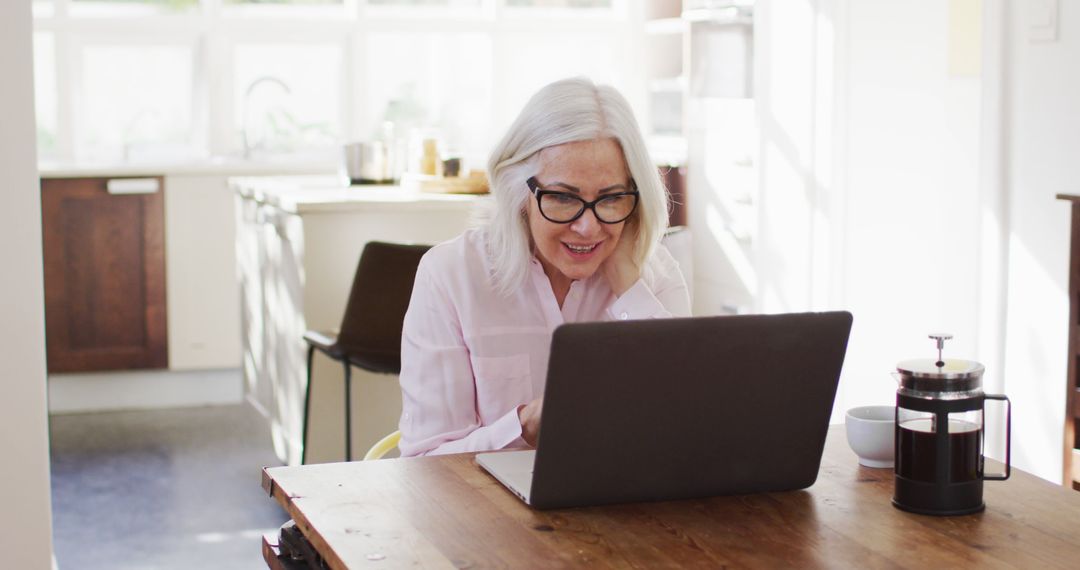 Senior Woman Using Laptop in Bright Kitchen - Free Images, Stock Photos and Pictures on Pikwizard.com