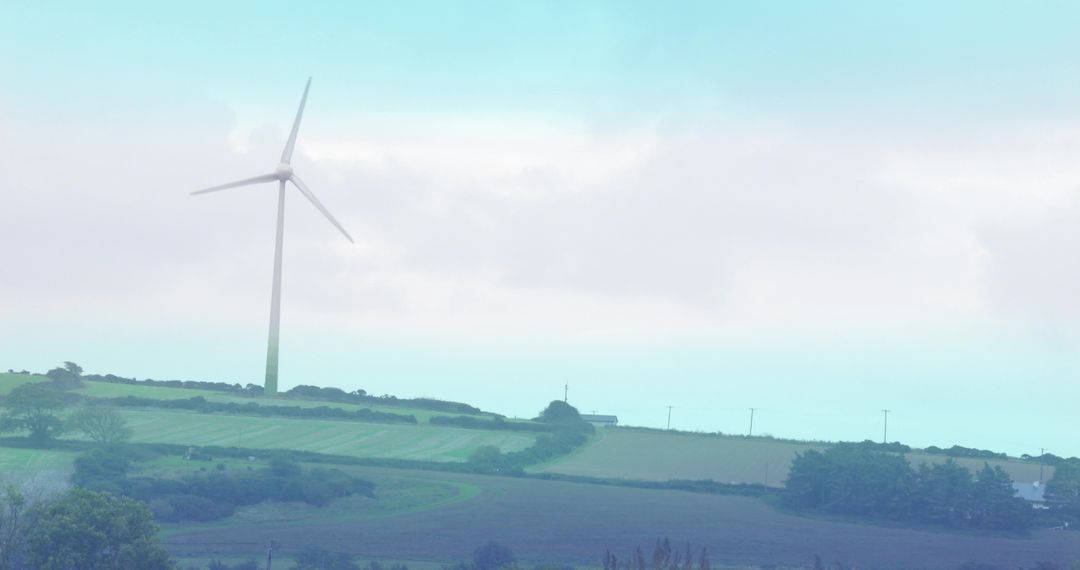 Wind turbine generating clean energy over rolling farmland with hedgerows and utility poles