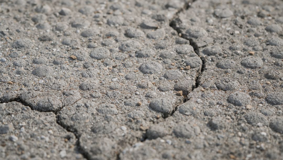 Cracked granular concrete with pebble aggregate and pitted surface texture close-up