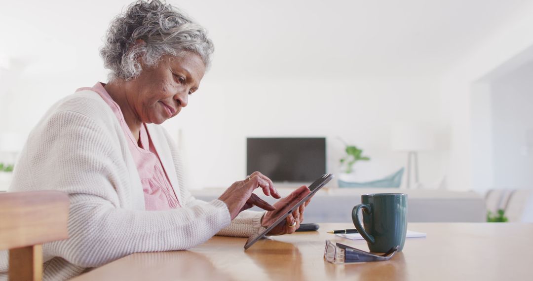 Senior Woman Using Tablet at Home with Coffee Mug - Free Images, Stock Photos and Pictures on Pikwizard.com