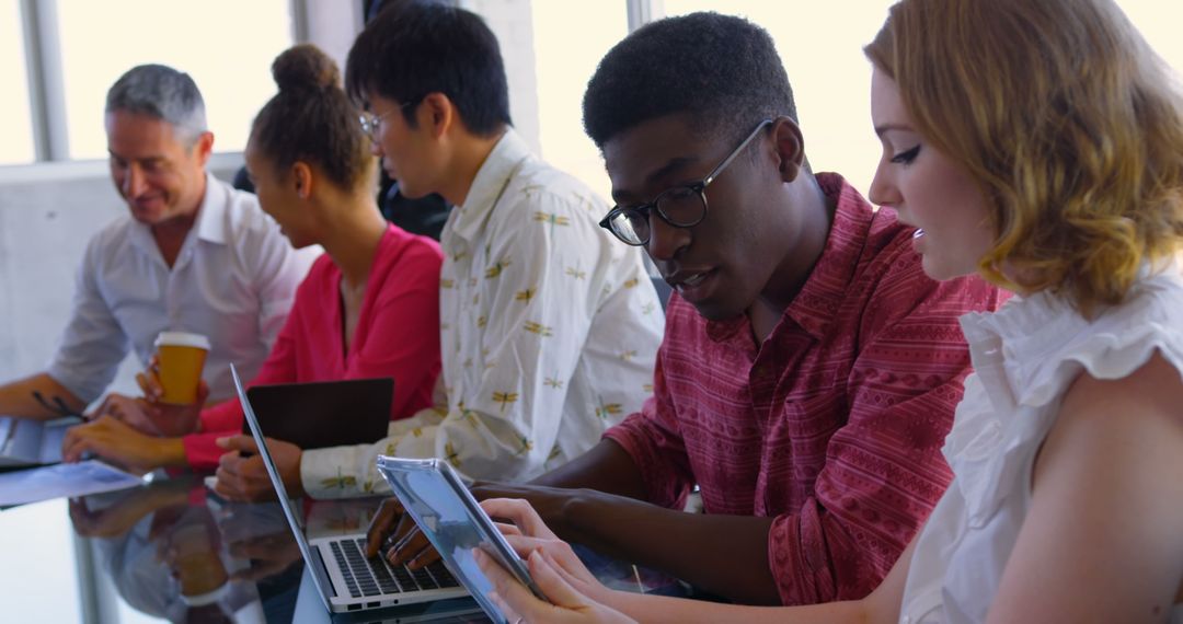 Diverse Team Collaborating on Devices in Modern Office