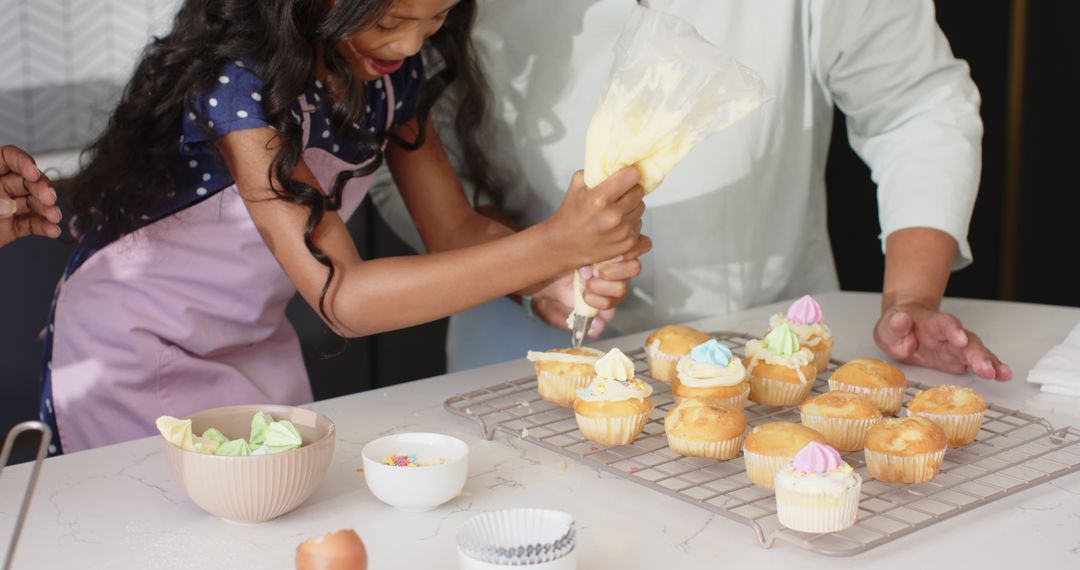 Child and Parent Decorating Cupcakes in Modern Kitchen