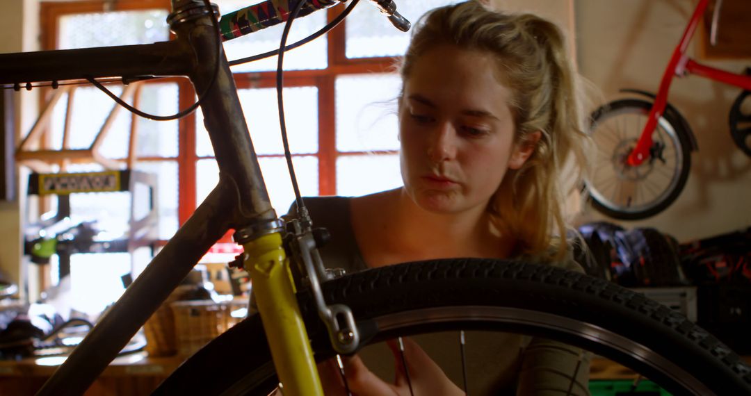 Focused Woman Repairing Bicycle in Workshop - Free Images, Stock Photos and Pictures on Pikwizard.com