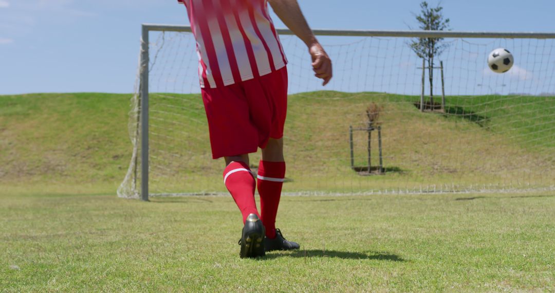 Soccer Player Kicking Ball Towards Goal on Sunny Day - Free Images, Stock Photos and Pictures on Pikwizard.com