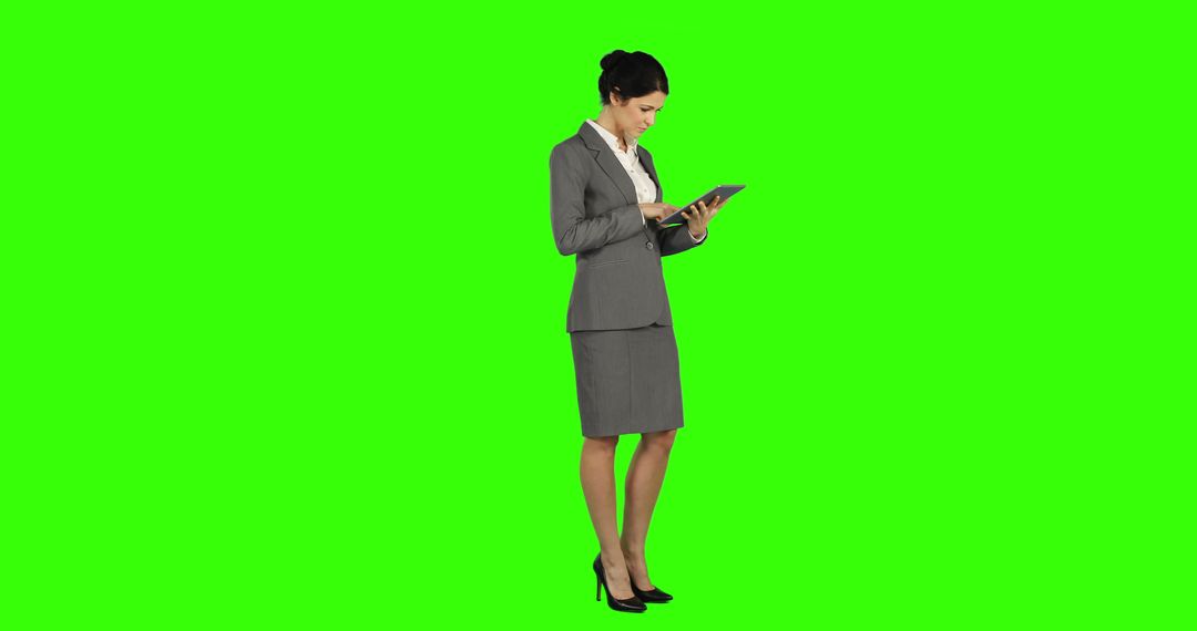 Businesswoman in Gray Suit Using Tablet on Green Screen - Free Images, Stock Photos and Pictures on Pikwizard.com