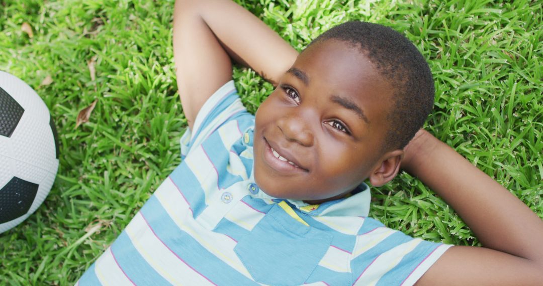 Smiling Black Boy Lying on Grass with Soccer Ball - Free Images, Stock Photos and Pictures on Pikwizard.com